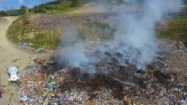 Aerial view away from firefighters, extinguishing a fire at a junkyard - reverse, drone shot