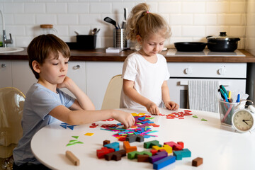 boy and little girl at home in the kitchen, sit at a round white table and play board games, life at home