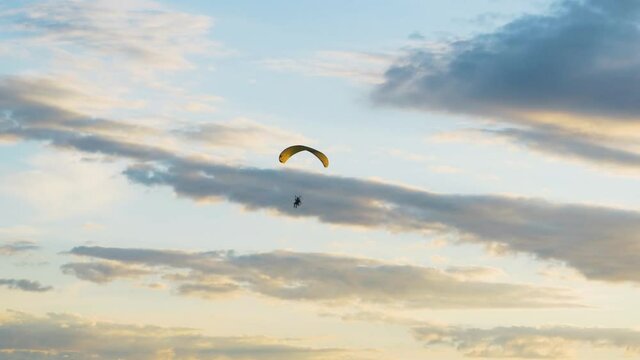 Silhouette man motor paragliding on vibrant midnight sun sky with clouds