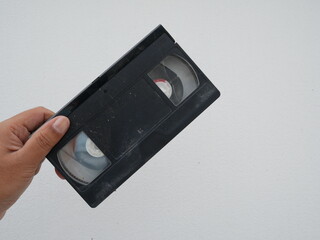 closeup of hand holding old video tape or vhs tape on white background.