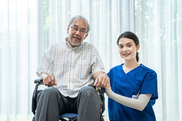 Portrait of old man sitting on wheelchair, nurse sitting beside.