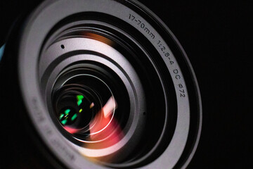 Close up of a camera lens lit with a soft light. There are red and green colors being reflected in...