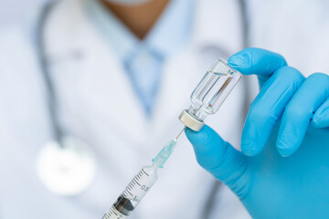 Doctor  hand in blue nitrile gloves holding flu, measles, coronavirus vaccine. covid-19 virus,...
