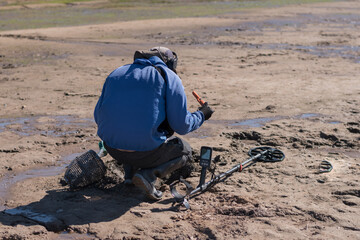 Man with a metal detector on a sea sandy beach.