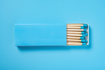 light blue matchbox and light blue match sticks on a light blue background