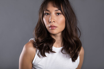 Close-up portrait of Asian woman. Serious girl on gray background