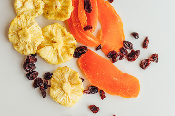 Mixed dry fruits on the light background. Pineapple, mango and cranberry. Healthy food and snack.