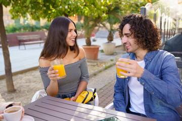 Couple of friends toasting while having a drink with their multi-ethnic group of friends