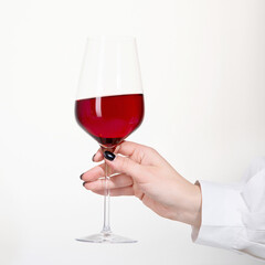 Young woman holding glass of rose wine on white background. Hand with black polish.