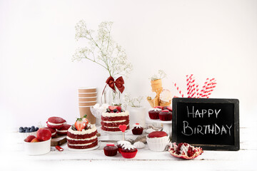 Delicious cake and cupcakes in red on white background. Table setting for celebration.