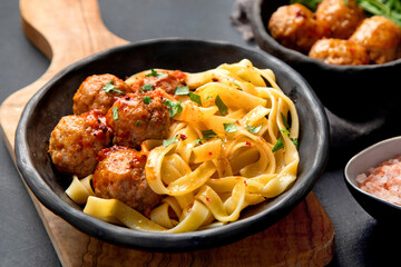 Tagliatelle with meatballs and tomato sauce on dark background. Italian food concept.