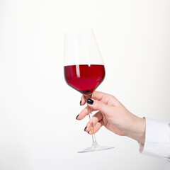 Young woman holding glass of rose wine on white background. Hand with black polish.
