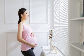 Fototapeta na wymiar asian pregnant woman near windows