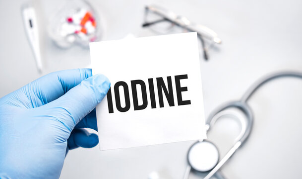 The doctor's blue - gloved hands show the word iodine - . a gloved hand on a white background. Medical concept. the medicine