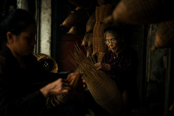 Obraz premium Craftsman making bamboo fish trap at old village, Hung Yen, Vietnam