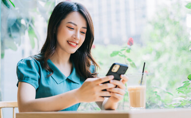 Young Asian woman using smartphone to working at cafe