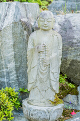 Miniature standing Buddha in garden.