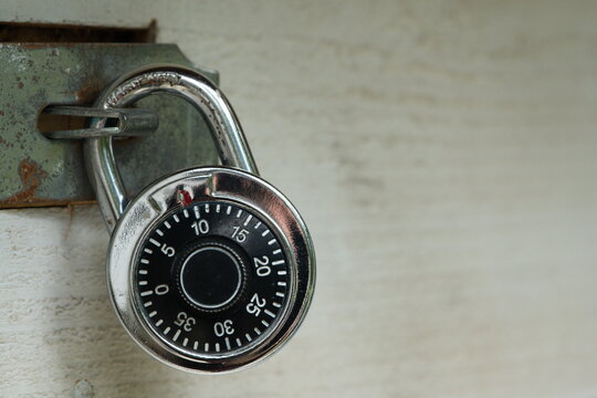Generic combination rotary lock on wooden gate with metal latch. Words "hardened" printed on the shackle