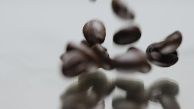 Slow motion macro coffee beans falling onto glass