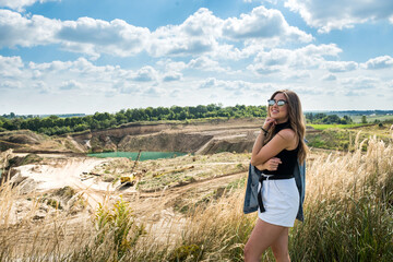 pretty young girl walks in a meadow. Village houses, forest as village life in summer time