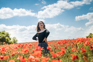 Fototapeta na wymiar pretty girl dreaming and enjoy nature at the field of red poppies.
