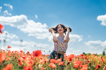 Beautiful young woman walking in poppy field on  summer day