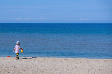 tourist season: a child walks on the beach. vacation by the sea