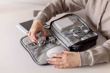 Top view female puts wires tablet modern electronic device equipment into comfortable storage bag