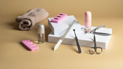 Manicure and pedicure tools mostly used in parlors and beauty salons. Nail file,  cuticle remover, pusher, scissors, towel  and nail polish on the podium for modern nail care and beauty concept.