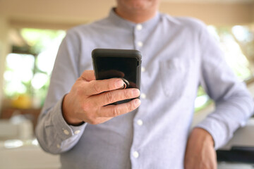 Businessman browsing or texting using his mobile phone. Close up view.