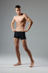 Fototapeta na wymiar naked man in black panties on a gray background pumped up muscles