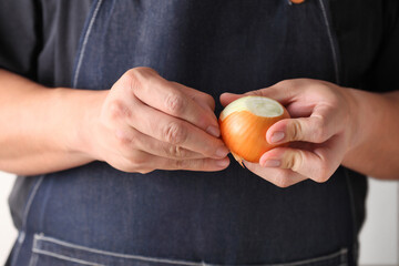 Chef's hands peeling an onion for cooking soup