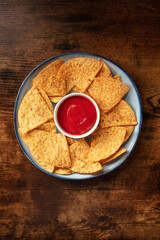 Nacho chips with a tomato salsa, served on a plate