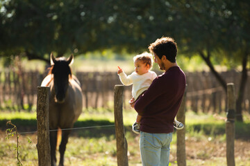 father showing horses to his little daughter