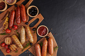 sausages and ingredients for cooking. Grilled sausage with the addition of herbs and and spices, vegetables, rosemary, thyme on the grill plate, Grilling food, bbq, barbecue, on stone table. Top view.