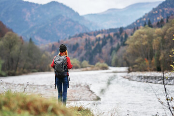 woman in a red sweater with a backpack in the mountains on nature near the river pond lake