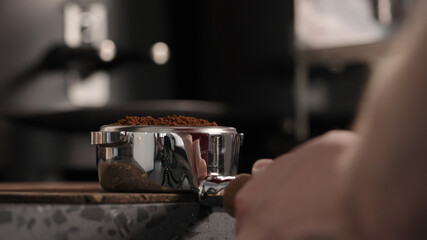 Fototapeta na wymiar closeup of barista tamping fresh coffee in bottomless portafilter