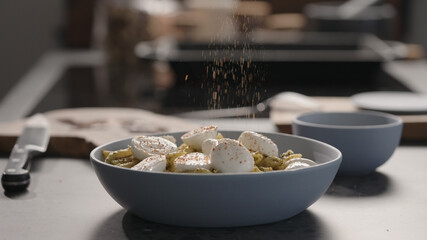 mozzarella to pesto penno in blue bowl on concrete countertop