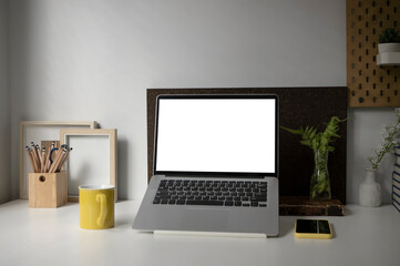 Mock up computer laptop, Coffe cup, houseplant, smart phone and pencil holder on white desk.