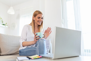 Young woman waving at laptop and talking to her friends via video call, girl student talking by video conference call, female teacher trainer tutoring by webcam, online training, e-coaching concept