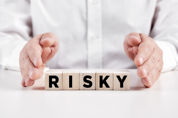 Male hands covers the wooden cubes with the word risky