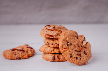 Piles of delicious chocolate chip cookies on a white plate with a milk bottle. Pastry utensils with white linen napkins on a wooden table. Delicious on a white plate with a bottle of milk.