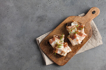 Ukrainian lard, pork lard, sprinkled with fresh chopped herbs on a wooden board. Copy space.