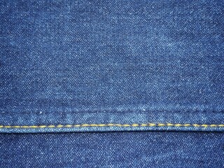 The fabric of the blue jeans is sewn along the line with yellow yarn. Use it as a design template. Use it as a background and wallpaper.