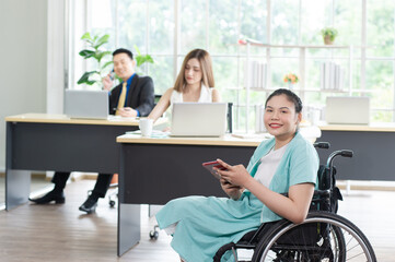Fototapeta na wymiar Portrait of Smiling young Asian woman office worker in wheelchair holding tablet look at camera, disabled people working with colleague at workplace