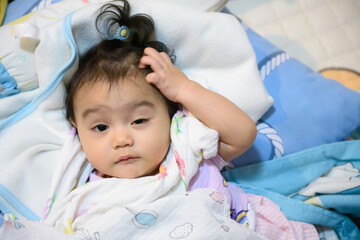 Cute little Asian baby girl wrapped in a blanket just woke up looking at camera , baby expression concept