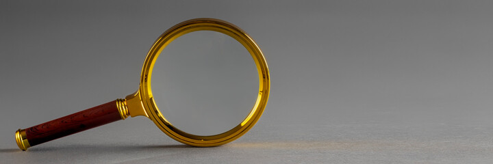 a golden magnifier on black paper background