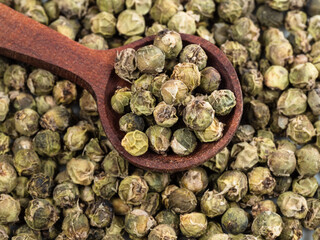 spoon on pile of green pepper peppercorns closeup
