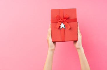 hands are holding red gift boxes on a pink background
