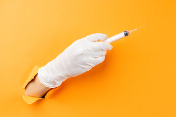 Hand holding syringe protruding from background